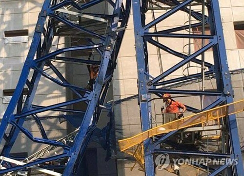 In this photo taken on May 22, 2017, firefighters examine a tower crane that broke killing two workers and injuring three at an apartment construction site in Namyangju, just northeast of Seoul. (Yonhap) 