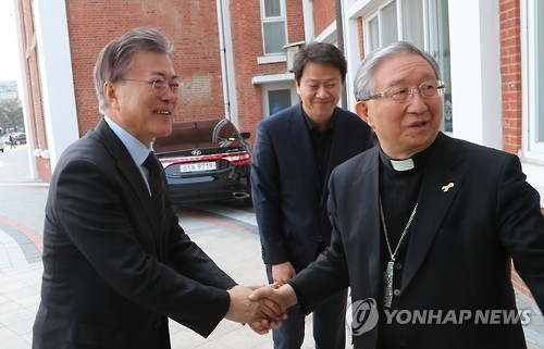 This file photo, taken on March 11, 2017, shows then presidential hopeful of the liberal Democratic Party Moon Jae-in (L) shaking hands with Archbishop Kim Hee-joong in Gwangju, 350 kilometers south of Seoul. Following his inauguration as the new South Korean president, Moon named Archbishop Kim as his special envoy to the Vatican. (Yonhap)