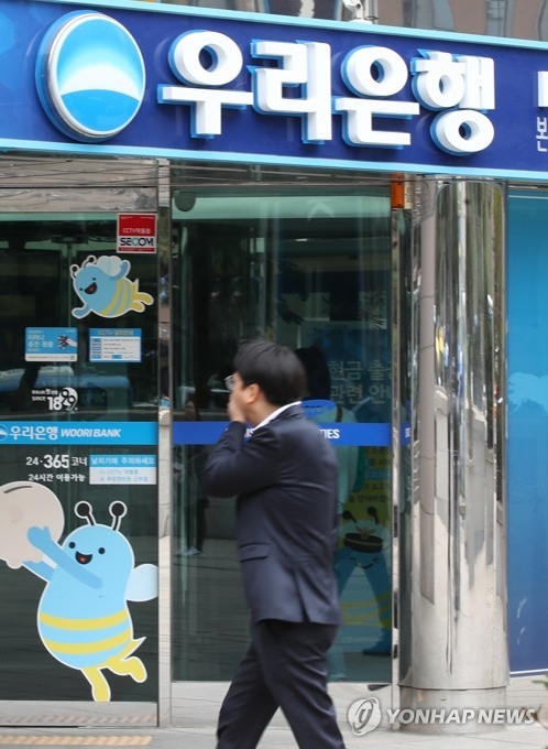 This file photo shows a man passing a Woori Bank in Seoul. (Yonhap)