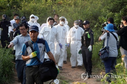 Police officers carry what is believed to be the body of a girl who went missing earlier this month in Gangjin, South Jeolla Province, on June 24, 2018. (Yonhap)