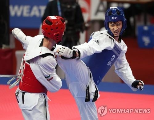 South Korea's Lee Dae-hoon (R) competes in the men's 68-kilogram division taekwondo sparring competition final against Amirmohammad Bakhshikalhori of Iran at the 18th Asian Games at Jakarta Convention Center Plenary Hall in Jakarta on Aug. 23, 2018. (Yonhap) 