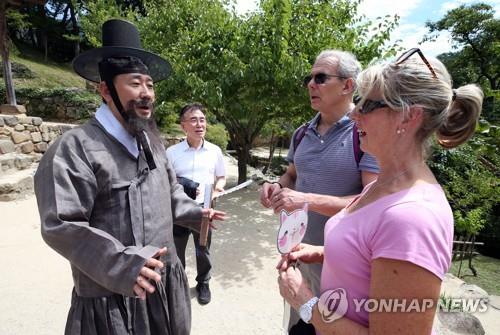 This photo provided by the Ministry of Culture, Sports and Tourism on Aug. 10, 2019, shows Minister Park Yang-woo (L) dressed in traditional Korean costume meeting foreign tourists in Damyang, South Jeolla Province, 340 kilometers south of Seoul. (PHOTO NOT FOR SALE) (Yonhap)