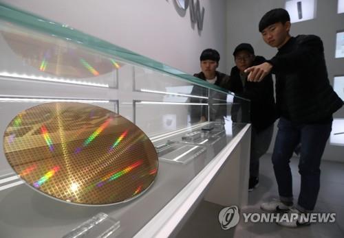 Visitors to Samsung Electronics Co.'s office in Seoul look at a wafer, a key material in semiconductors, displayed in the company promotion center on Oct. 31, 2018. (Yonhap)