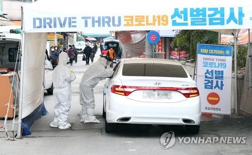 A medical worker collects a sample from a citizen in an automobile at a drive-through clinic in Daejeon, 160 kilometers south of Seoul, on March 1, 2020, to test for the new coronavirus. (Yonhap)