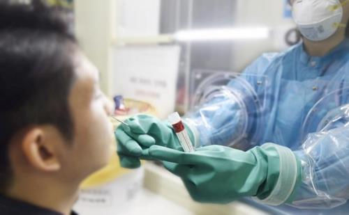 A nurse takes a sample from a man to test for the new coronavirus through a "glove wall" at Boramae Medical Center in Seoul, in this undated photo released by the hospital on March 16, 2020. (PHOTO NOT FOR SALE) (Yonhap)