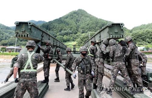 Engineering soldiers build a makeshift bridge on a flood-damaged bridge over a stream in Inje, a town in South Korea's northeast province of Gangwon, on Aug. 12, 2020, after residents living across the stream were stranded for a week following heavy rain in the region. (Yonhap)