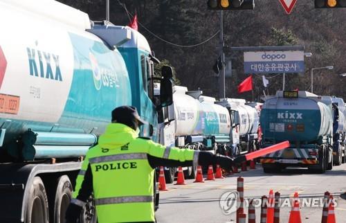 Tankers driven by nonunion drivers pass by ones halted by striking drivers under police protection in front of Daehan Oil Pipeline Corp.'s Seoul branch on Nov. 30, 2022, amid a nationwide strike by unionized truckers. Truck drivers went on strike nationwide on Nov. 24, demanding the government extend temporary rules guaranteeing minimum freight rates, citing high fuel prices. (Yonhap)