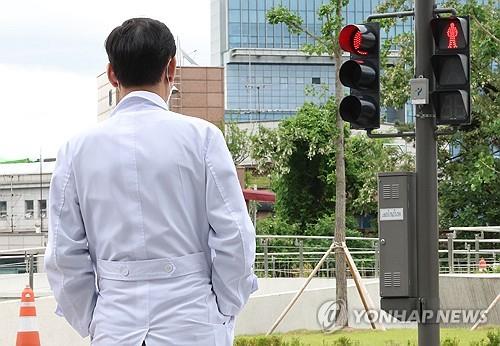 A doctor waits for the traffic signal to change at a major hospital in Seoul on May 23, 2024. (Yonhap)