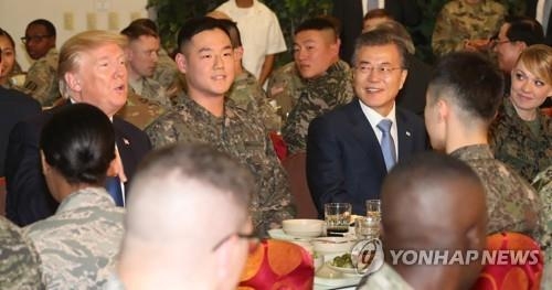 韓米連合軍司令部の将兵たちと昼食を取るトランプ大統領（左端）と文大統領（左から３人目）＝７日、平沢（写真共同取材団＝聯合ニュース）