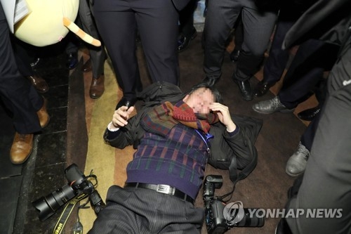 暴行を受けて倒れている韓国人記者＝１４日、北京（聯合ニュース）
