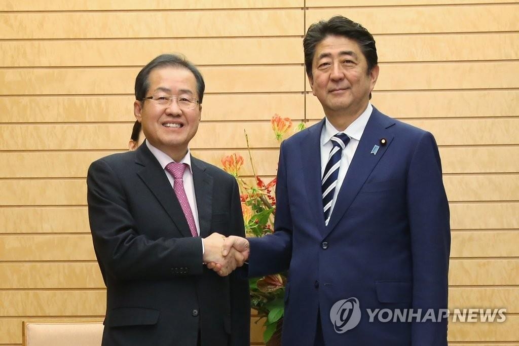 安倍首相と握手する洪代表（左、自由韓国党提供）＝１４日、東京（聯合ニュース）