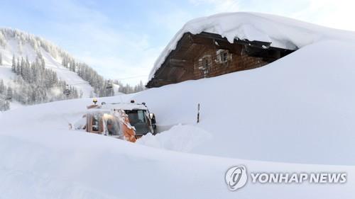 오스트리아 잘츠부르크 인근 마을에 내린 눈이 집 지붕까지 쌓인 가운데 제설차가 11일(현지시간) 집 앞으로 길을 내고 있다. [AP=연합뉴스] 