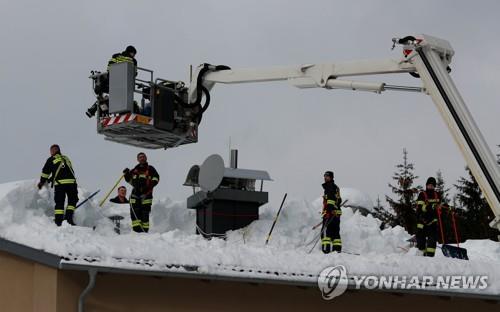 오스트리아 로제나우에서 14일(현지시간) 소방대원들이 건물 지붕의 눈을 치우고 있다. [로이터=연합뉴스]