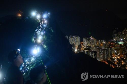 휴대전화 불빛과 레이저빔을 비추는 '홍콩의 길' 참가자들