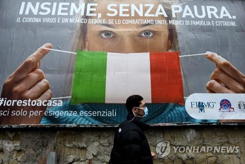 이탈리아 코로나19 포스터 앞 지나는 남성 [AFP=연합뉴스]
