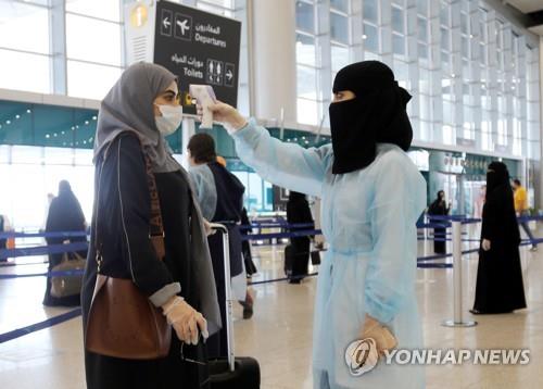사우디아라비아 리야드 공항에서 국내선을 타는 승객의 체온을 재는 공항 직원