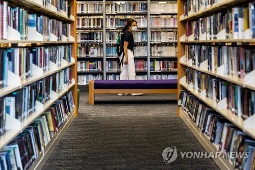 한 홍콩 여성이 4일 공공도서관 서가에서 책을 찾고 있다. 홍콩의 공공도서관에서는 조슈아 웡을 비롯한 주요 민주화 인사들의 저서가 모조리 사라져 대출할 수 없다.[AFP=연합뉴스]