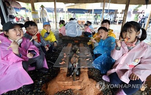와일드푸드축제장서 직접 잡은 물고기 구워 먹는 어린이들.