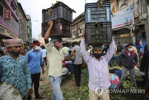 인도 벵갈루루의 시장에서 마스크를 쓰고 짐을 옮기는 인부. [AP=연합뉴스]