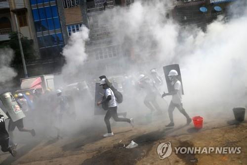 양곤에서 시위대가 최루탄 속에서 뛰고 있다.