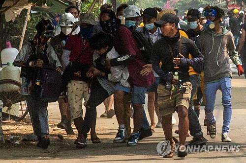 양곤에서 군경의 총탄에 맞은 시위 참여자를 동료들이 옮기는모습 2021.3.29