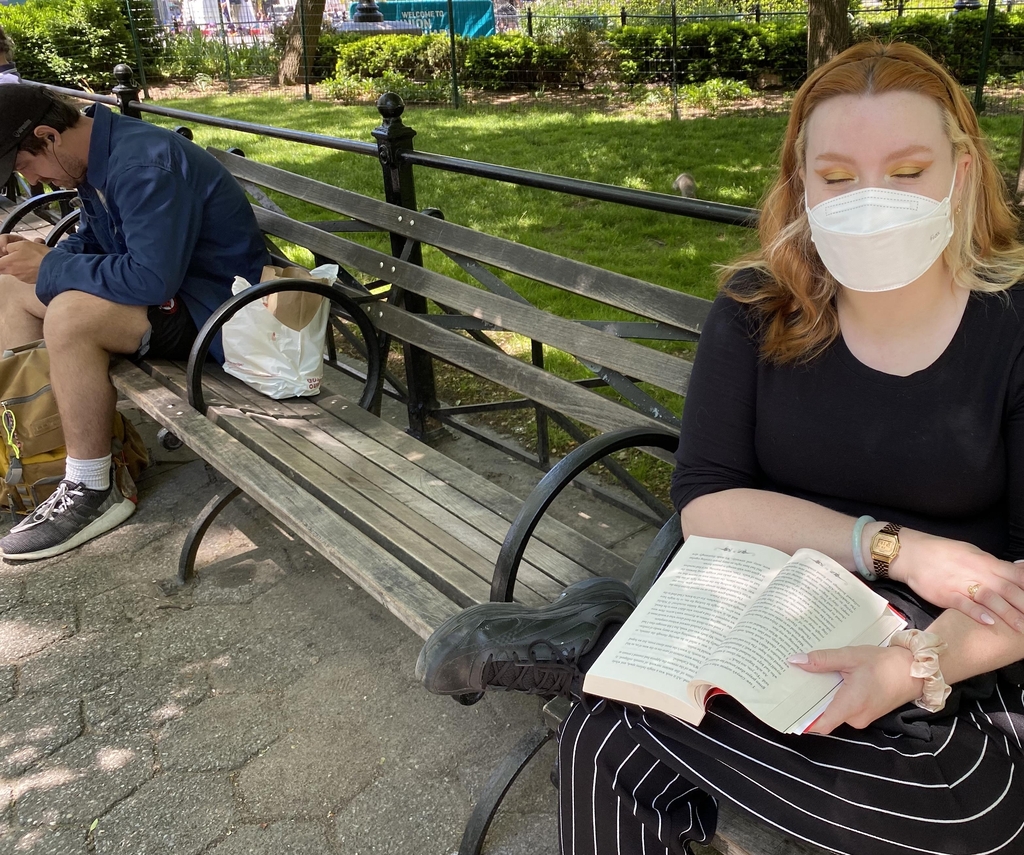 뉴욕시 유니언스퀘어에서 마스크를 쓰고 책을 읽는 여성과 '노마스크' 남성 