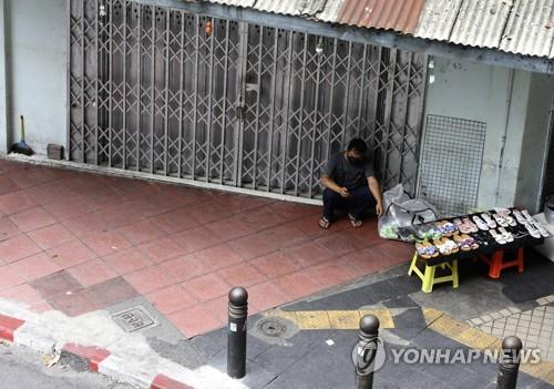 봉쇄 조치로 문을 닫은 방콕 시내 상점 앞에서 손님을 기다리는 노점상. 2021.7.12