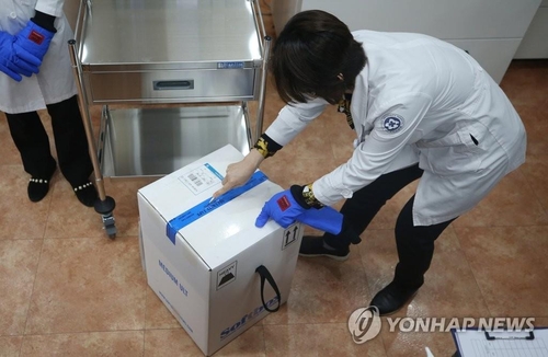 Una trabajadora sanitaria abre una caja con las primeras dosis de la vacuna contra el coronavirus del gigante farmacéutico estadounidense Pfizer Inc., el 26 de febrero de 2021, en un hospital de Gwangju, a unos 330 kilómetros al sur de Seúl.