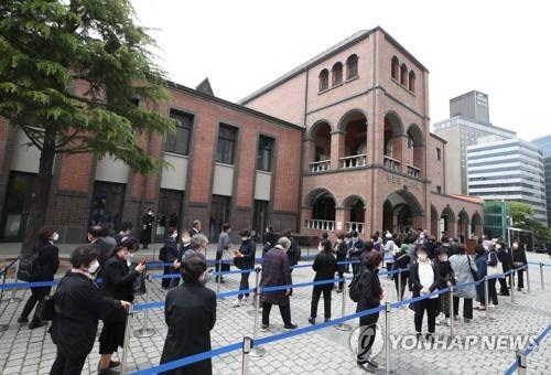 La gente espera en fila para ingresar a la catedral de Myeongdong, en el centro de Seúl, el 28 de abril de 2021, para rendir homenaje al fallecido cardenal Nicholas Cheong Jin-suk, que falleció el día anterior. 