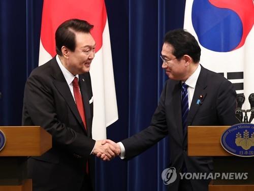 El presidente surcoreano, Yoon Suk Yeol (izda.), estrecha la mano del primer ministro japonés, Fumio Kishida, el 16 de marzo de 2023, en Tokio, al final de la conferencia de prensa conjunta posterior a su cumbre.