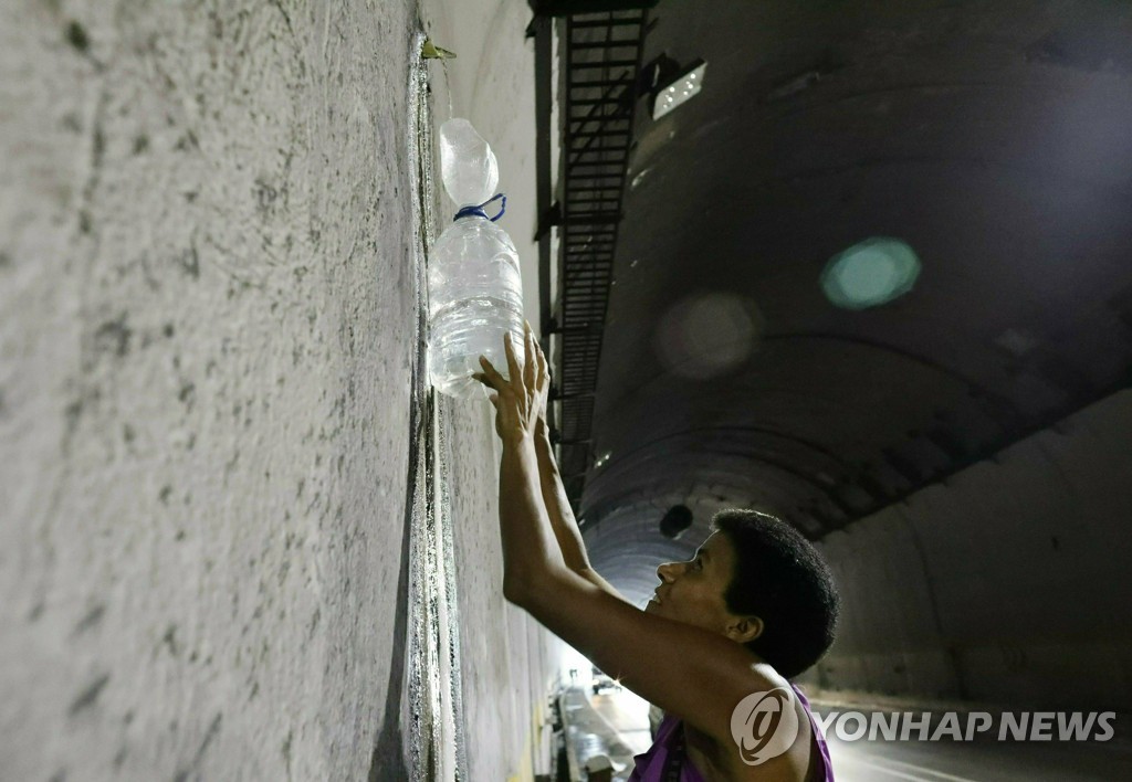 고속도로 터널에서 새는 물을 받아가는 베네수엘라 주민