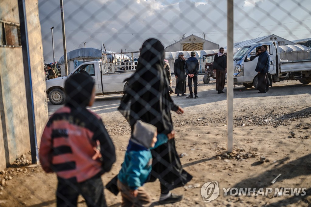 17일(현지시간) 시리아 북동부에 있는 수용소에서 IS에서 탈출한 프랑스 여성이 자녀와 함께 걷고 있다. [AFP=연합뉴스 자료사진]