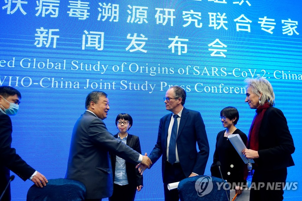 WHO 전문가 피터 벤 엠바렉(오른쪽)이 9일 기자회견 후 중국 측 전문가 량완녠과 악수하고 있다. [로이터=연합뉴스]