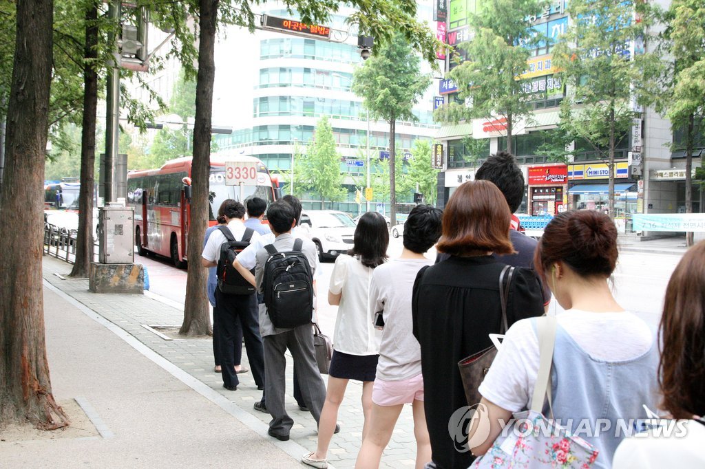광역버스 입석금지로 인해 정류장을 무정차 통과하는 버스를 보내며 시민들이 줄을 길게 늘어서 있다. (연합뉴스 자료사진)