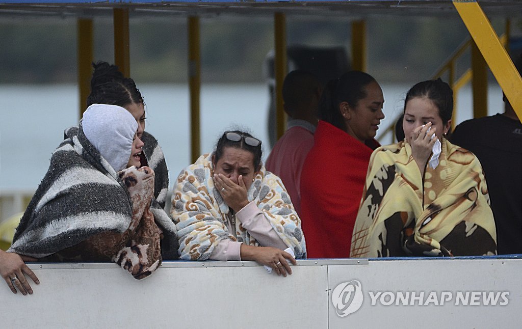 유람선 침몰 사고가 발생한 콜롬비아 과타페에서 25일(현지시간) 구조된 사람들이 실종 상태인 가족·친구들의 생환 소식을 기다리며 슬픔에 잠겨있다.[AP=연합뉴스]