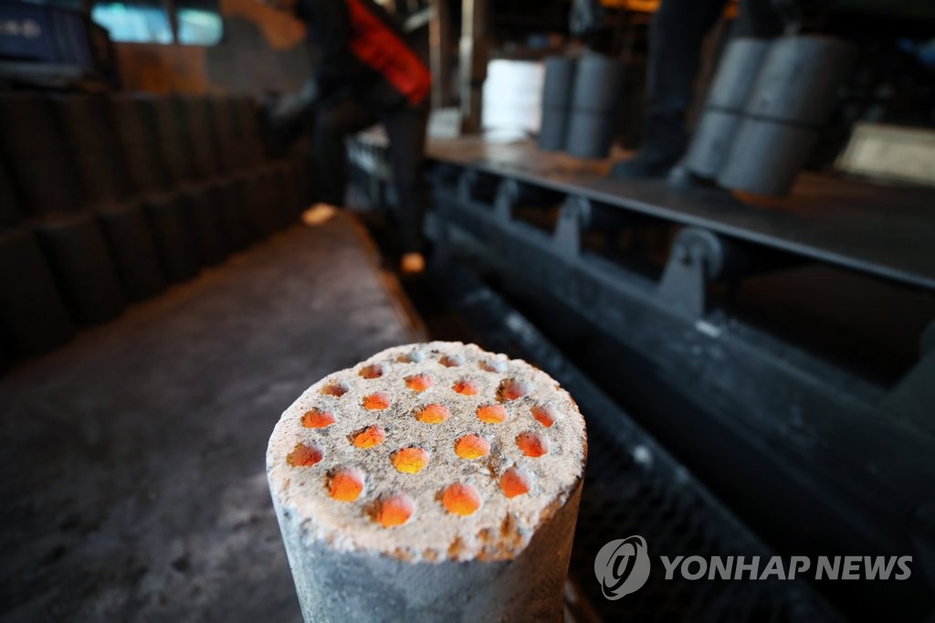 2017년 11월 27일 서울의 한 연탄공장에서 직원들이 연탄으로 언 몸을 녹이며 연탄을 옮기고 있다. [연합뉴스 자료사진]