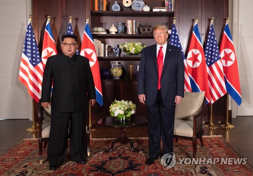 U.S. President Donald Trump (R) poses with North Korean leader Kim Jong-un at the Capella Hotel in Singapore on June 12, 2018, while having a one-on-one summit there, in this photo captured from the Twitter account of White House social media director Dan Scavino. (Yonhap)