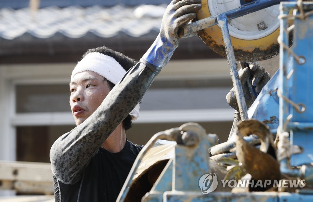 일본 폭우 피해지서 폭염과 싸우며 복구 작업하는 남성