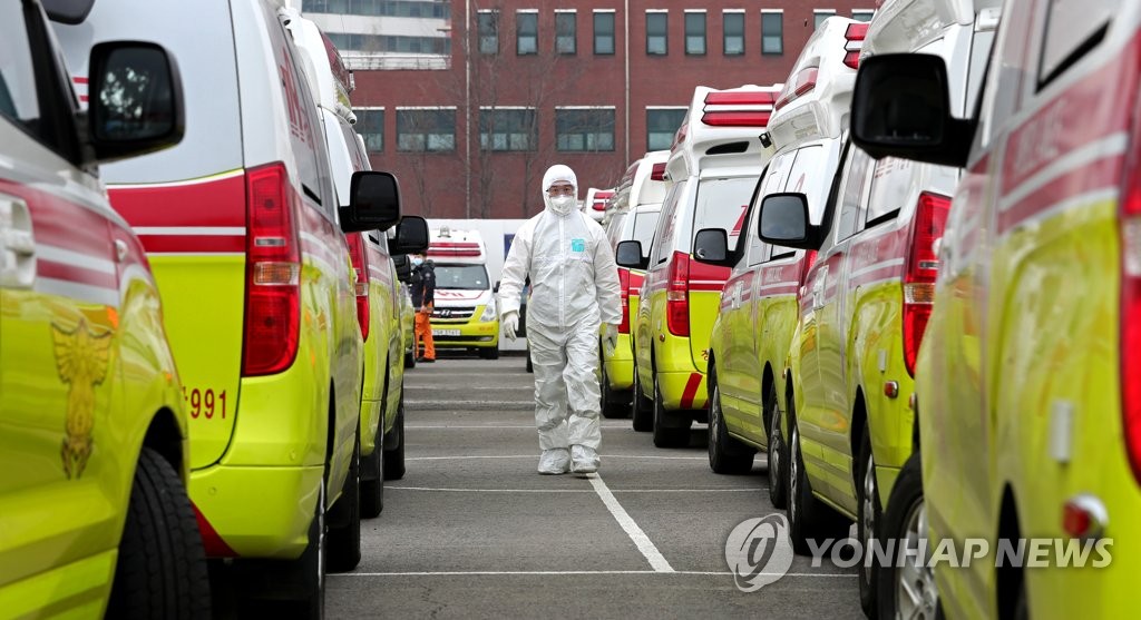 A health worker walks by ambulances in a parking lot in Daegu on March 1, 2020. (Yonhap)