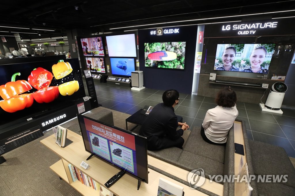 This file photo taken April 29, 2020, shows consumers looking at TVs at an electronics store in Seoul. (Yonhap)