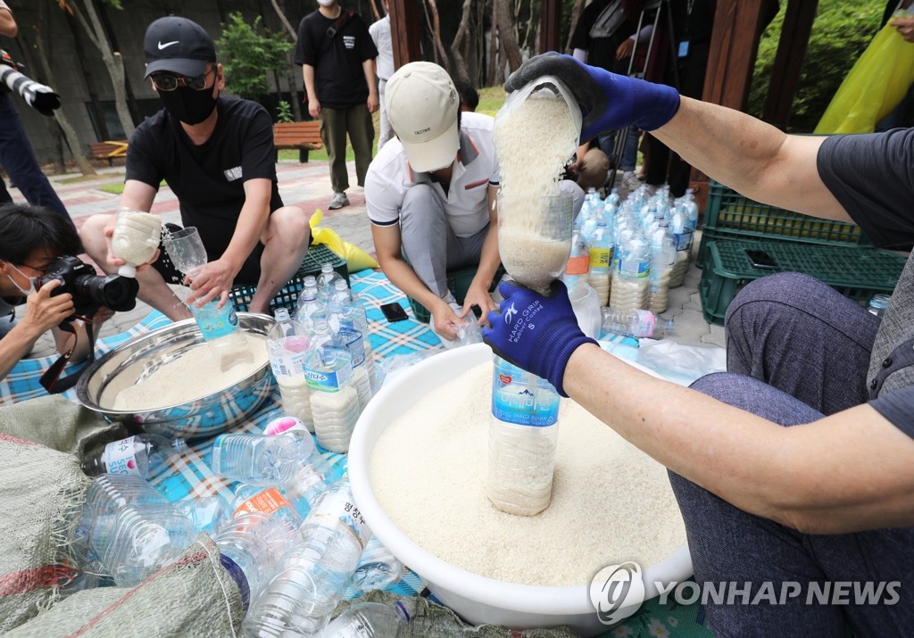 Defector activists put rice into PET bottles at a park in Seoul on June 18, 2020. They plan to drift them into North Korea via waters off the western island of Ganghwa bordering North Korea, despite the government's crackdown on their anti-Pyongyang activities, including the flying of balloons containing anti-Kim Jong-un leaflets into the North. (Yonhap)