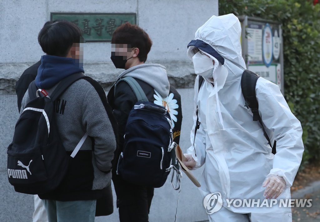 A student taking the College Scholastic Ability Test arrives in a protective suit at a high school in Incheon, west of Seoul, on Dec. 3, 2020. (Yonhap)