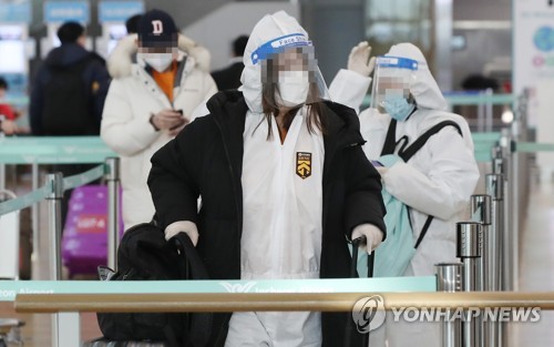Passengers clad in protective gear wait at a check-in counter at Incheon International Airport, west of Seoul, on Jan. 14, 2021 (Yonhap)