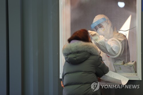 A medical worker collects a specimen from a woman at a temporary COVID-19 screening station set up in front of Seoul Station on Jan. 16, 2020. (Yonhap)