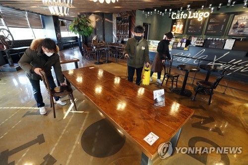 Employees of a cafe in the southeastern city of Daegu set up tables on Jan. 17, 2021, one day before the government eased social distancing regulations on coffee shops. (Yonhap)