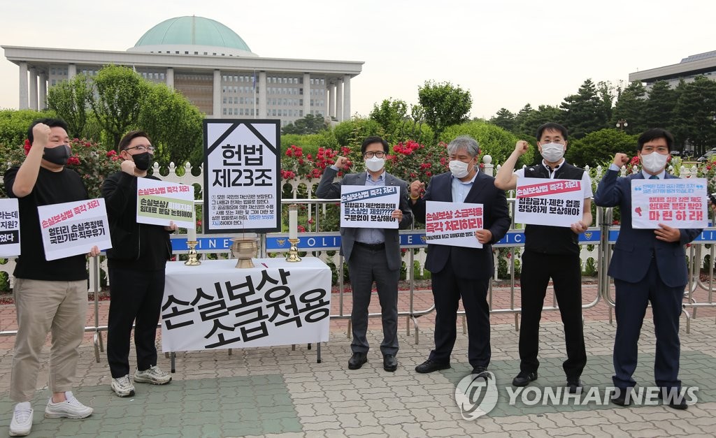 Small merchants and other protestors from civic groups hold a rally in front of the National Assembly in Seoul on June 7, 2021, to call for the introduction of a bill that would enable retroactive compensation for losses faced by small businesses due to official antivirus measures. (Yonhap)