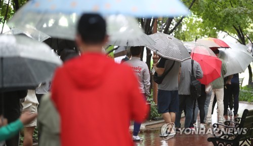 Des citoyens font la queue sous la pluie pour se faire dépister pour le nouveau coronavirus (Covid-19) dans un parc à Daegu, le lundi 11 octobre 2021.