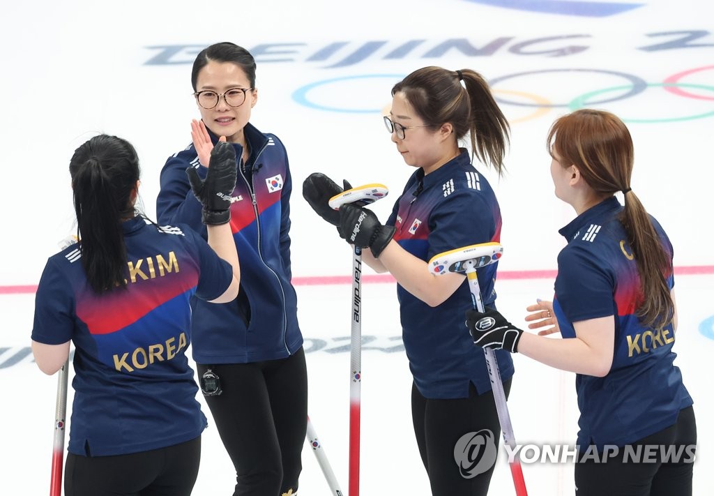 Les curleuses sud-coréennes Kim Kyeong-ae, Kim Eun-jung, Kim Seon-yeong et Kim Cho-hi (de gauche à droite) célèbrent un point marqué contre la Suède lors d'un match de curling féminin du tournoi toutes rondes des Jeux olympiques d'hiver de Pékin 2022, au Centre aquatique national de Pékin, le jeudi 17 février 2022.
