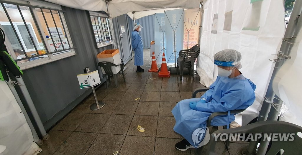 Medical workers stand by at a quiet COVID-19 testing booth in Seoul's central district of Jongno, in this photo taken May 18, 2022, amid a decline in the infection numbers. (Yonhap)