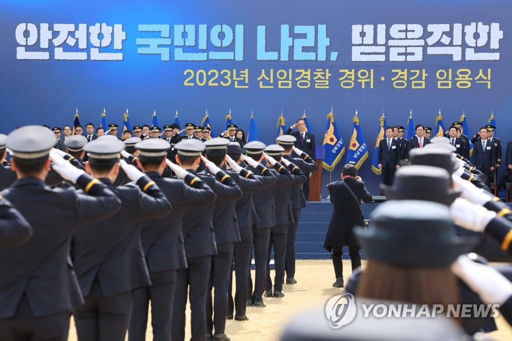 Prime Minister Han Duck-soo (C, on the podium) salutes during a joint commissioning ceremony for new police officers at the Korea National Police University in Asan, some 90 kilometers south of Seoul, on March 16, 2023. (Yonhap)